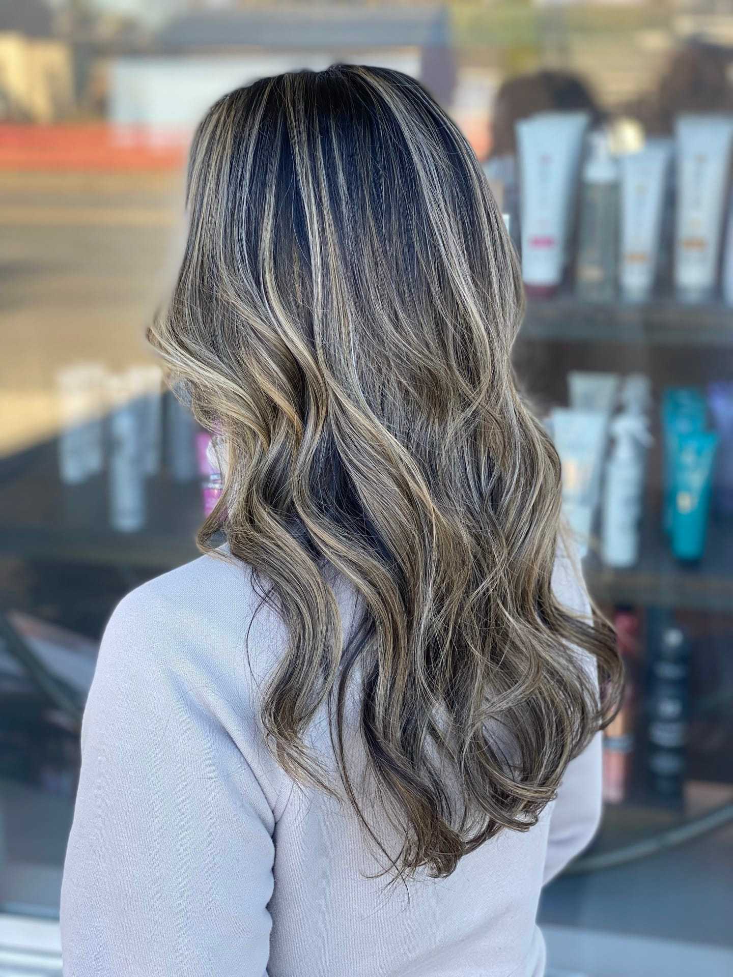 Long wavy hair with highlights in a salon setting.