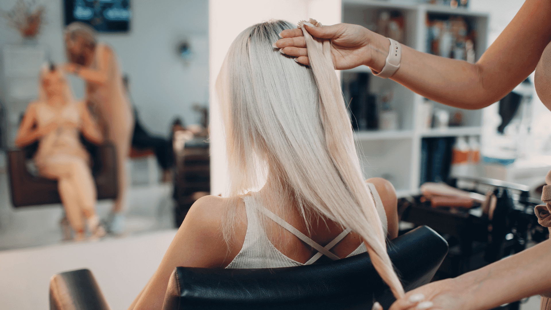 Hairstylist brushing long blonde hair in a salon chair.