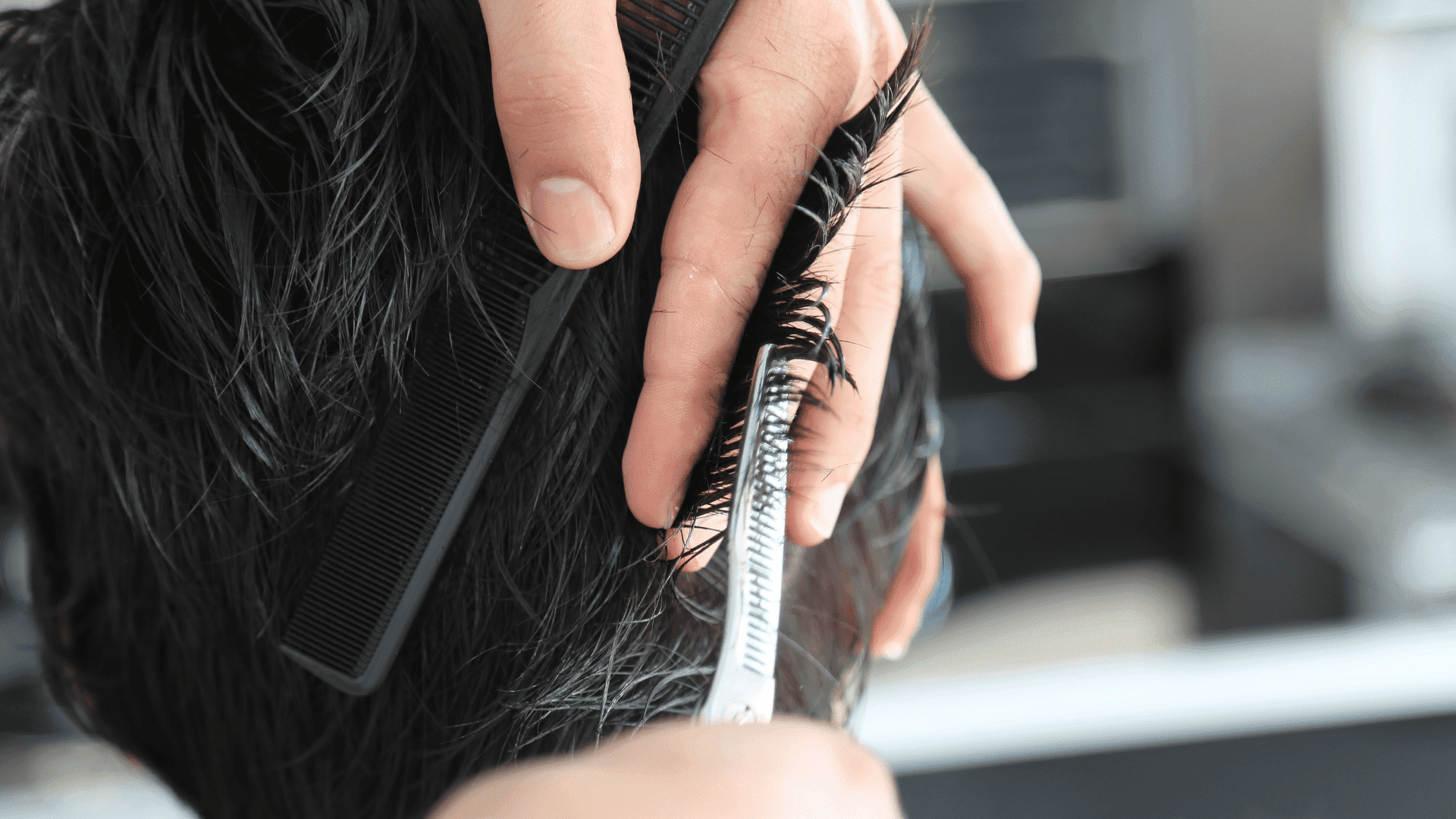 Hair being trimmed with scissors and comb in a close-up shot at a salon.
